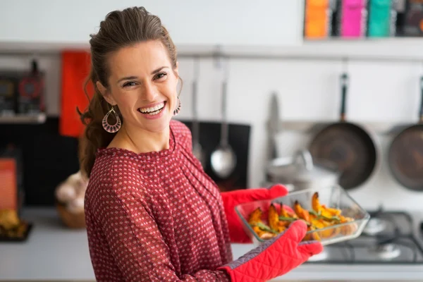 Portrait of happy young housewife holding baked pumpkin — Stock Photo, Image