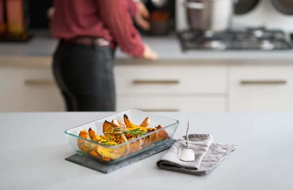 Closeup on pan of baked pumpkin and young housewife in backgroun — Stock Photo, Image