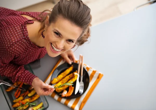 Porträt einer glücklichen jungen Hausfrau, die gebackenen Kürbis serviert — Stockfoto