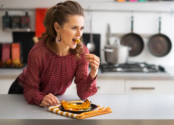 Портрет молодой женщины, поедающей запечённую тыкву на кухне — стоковое фото
