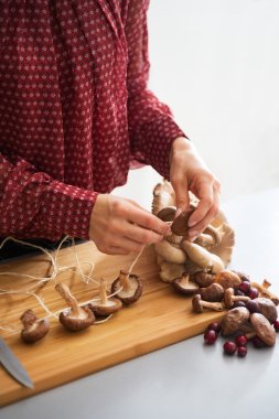Closeup on young housewife stringing mushrooms on string clipart