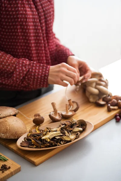Gros plan sur les champignons séchés et jeune femme au foyer ficelant des champignons — Photo