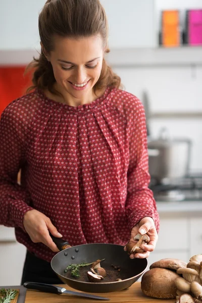 Gelukkig jonge huisvrouw koken paddestoelen — Stockfoto