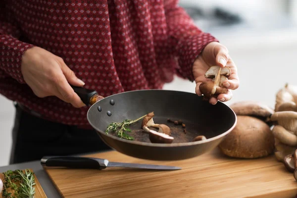 Closeup on young housewife cooking mushrooms — Stock Photo, Image