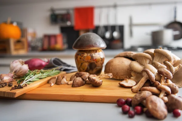 Close-up op pot van ingemaakte paddenstoel op snijplank — Stockfoto