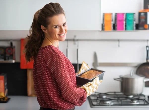 Glückliche junge Hausfrau hält Backform mit Brot — Stockfoto