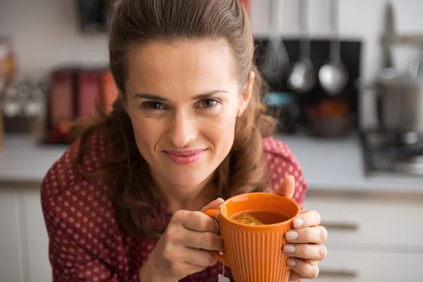 Retrato de feliz jovem dona de casa bebendo chá na cozinha — Fotografia de Stock