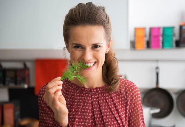 Glad ung hemmafru äta färsk dill — Stockfoto