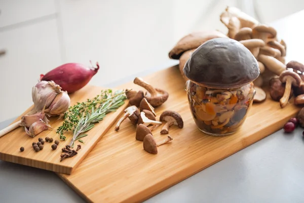 Closeup on jar of pickled mushroom on cutting board — Stock Photo, Image