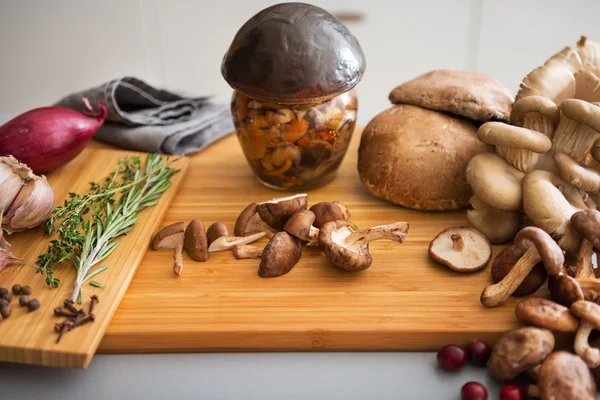 Close-up op pot van ingemaakte paddenstoel op snijplank — Stockfoto