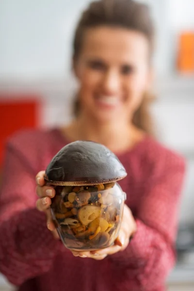 Close-up em feliz jovem dona de casa mostrando frasco de cogumelos em conserva — Fotografia de Stock