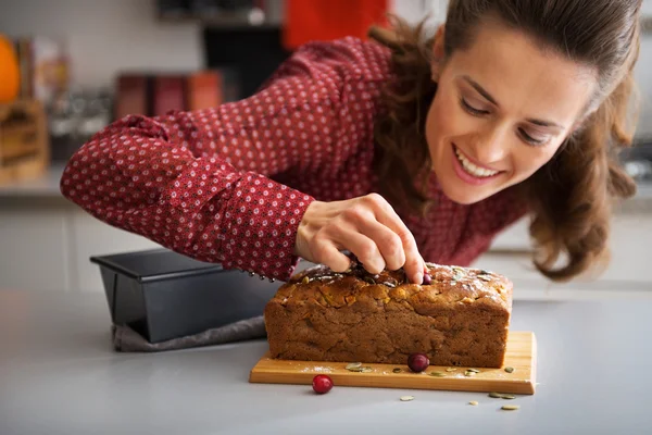 Closeup on happy young housewife decorating freshly baked pumpki — Stock Photo, Image