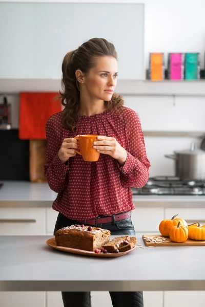 Junge Hausfrau trinkt Tee mit frisch gebackenem Kürbisbrot — Stockfoto