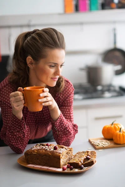 Young housewife drinking tea with freshly baked pumpkin bread wi — Stock Photo, Image