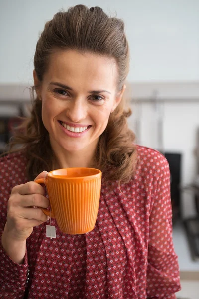 Porträt einer glücklichen jungen Hausfrau, die Tee in der Küche trinkt — Stockfoto