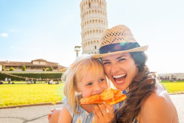 Mutlu anne ve bebek kız önünde pizza yemek portresi