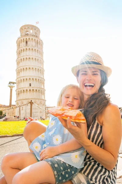 Happy mother and baby girl eating pizza in front of leaning towe — Stock Photo, Image