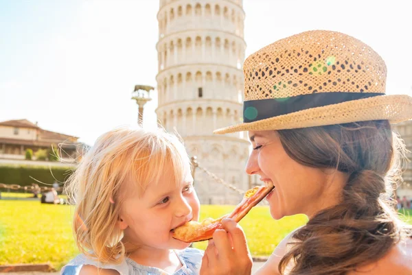 Mãe feliz e bebê menina comendo pizza na frente de inclinação towe — Fotografia de Stock