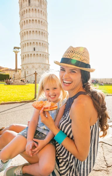 Mãe feliz e bebê menina comendo pizza na frente de inclinação towe — Fotografia de Stock