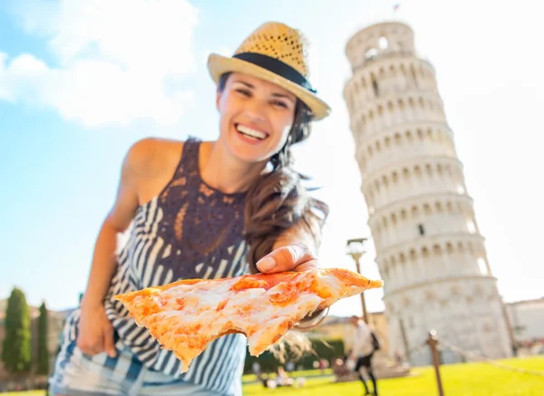 Smiling young woman giving pizza in front of leaning tower of pi — Stock Photo, Image