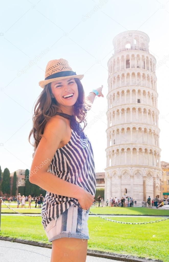 Happy young woman pointing on leaning tower of pisa, tuscany, it