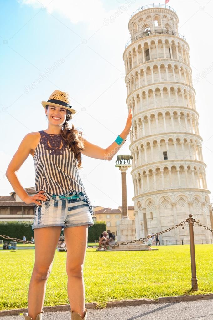 Funny young woman supporting leaning tower of pisa, tuscany, ita