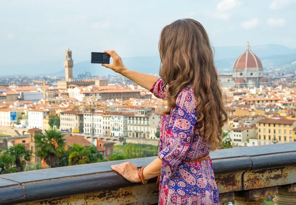 Smiling young woman taking photo of panoramic view of florence, italy. rear view — Stock fotografie