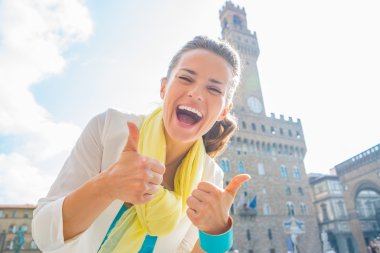 Happy young woman showing thumbs up in front of palazzo vecchio  clipart