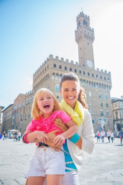 Portrait of smiling mother and baby girl in front of palazzo vec clipart