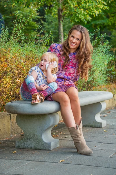 Mère et bébé fille parlant téléphone cellulaire dans le parc de la ville — Photo