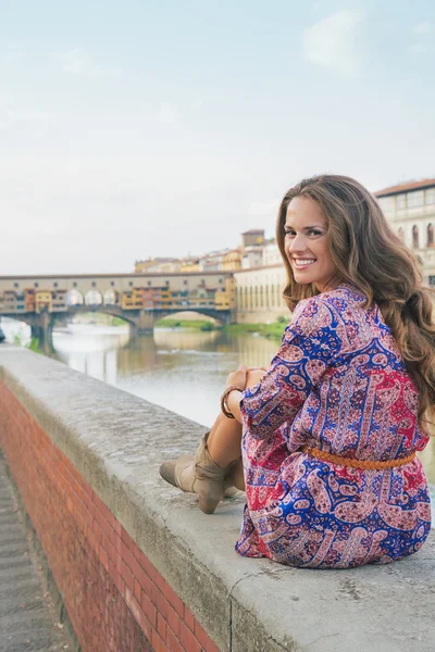 Szczęśliwa młoda kobieta siedzi w pobliżu ponte vecchio we Florencji, Włochy — Zdjęcie stockowe