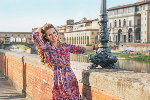 Giovane donna sorridente sul terrapieno vicino a ponte vecchio a firenze — Foto Stock