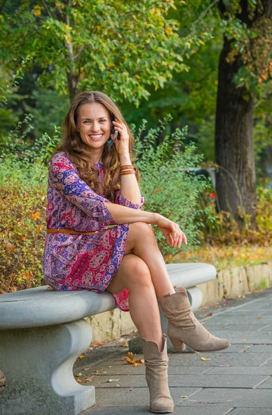 Happy young woman talking cell phone in city park — Stock Photo, Image