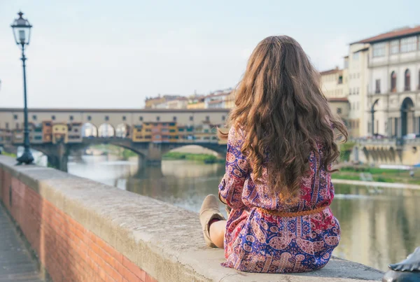 Young woman sitting near ponte vecchio in florence, italy. rear — Stock Photo, Image