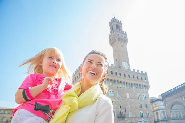 Happy mother and baby girl looking into distance in front of pal