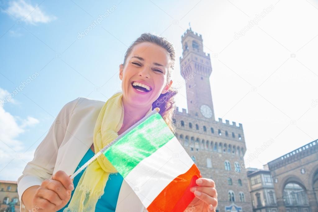 Happy young woman showing flag in front of palazzo vecchio in fl