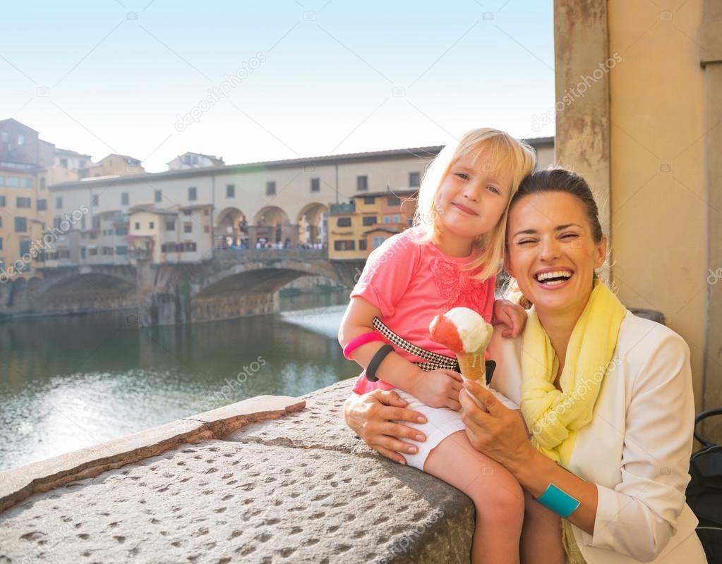 Portrait of happy mother and baby girl eating ice cream near pon