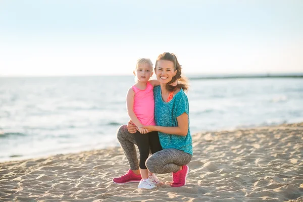 Portrait of healthy mother and baby girl on beach in the evening — Stock Photo, Image