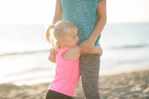 Baby flicka kramar mamma på stranden på kvällen — Stockfoto