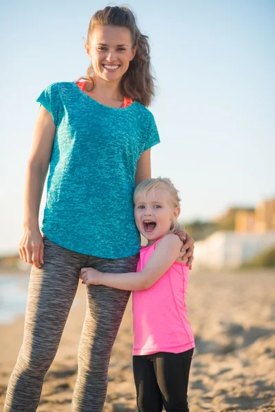 Glücklich Baby Mädchen umarmt Mutter am Strand am Abend — Stockfoto