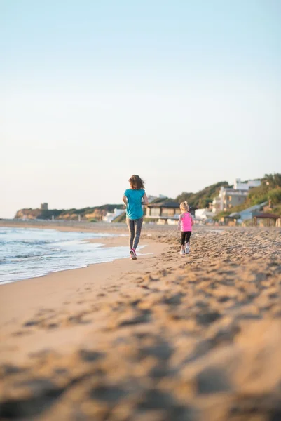 Madre sana y niña corriendo en la playa por la noche. re — Foto de Stock