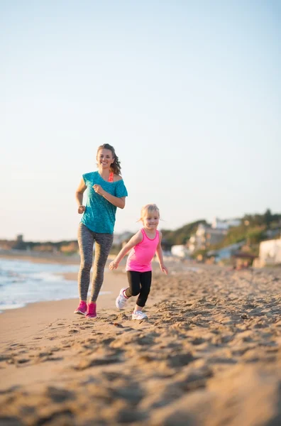 Здорова мати і дівчинка біжить на пляжі ввечері — стокове фото