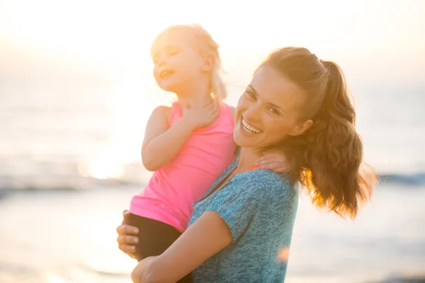 Portrait of healthy mother and baby girl on beach in the evening — Stock Photo, Image
