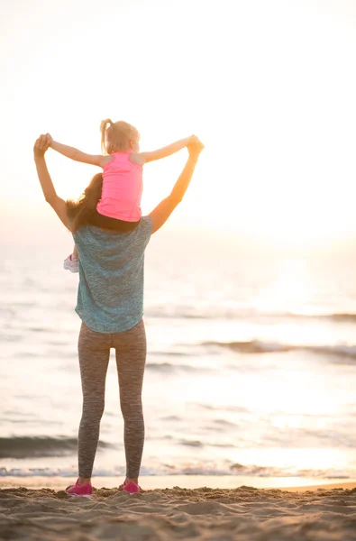 Baby-Mädchen sitzt auf den Schultern der Mutter und freut sich, während sie unterwegs ist — Stockfoto