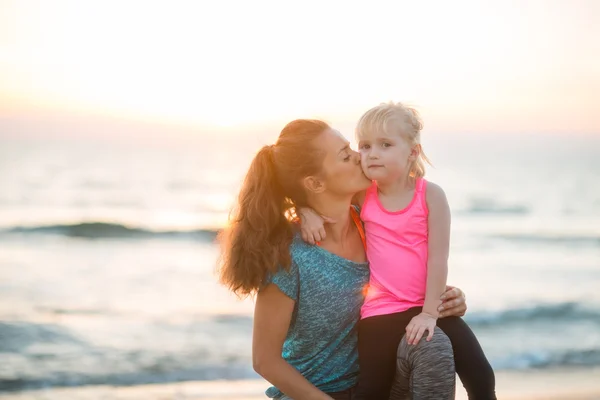 Healthy mother and baby girl kissing on beach in the evening — Stock Photo, Image