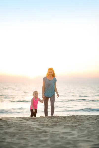 Mãe saudável e bebê menina andando na praia à noite — Fotografia de Stock