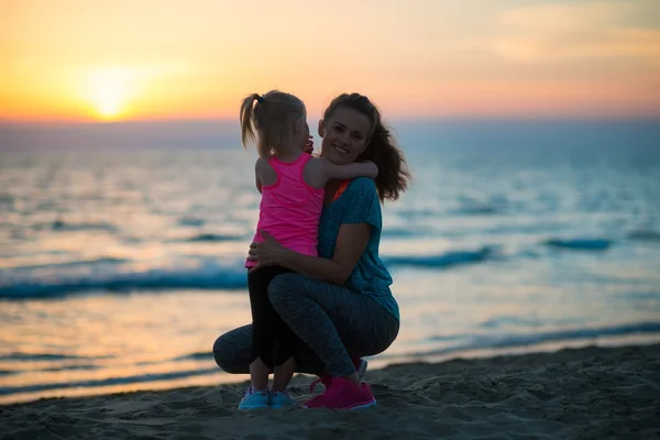 Silhouette di madre e bambina che si abbracciano sulla spiaggia — Foto Stock