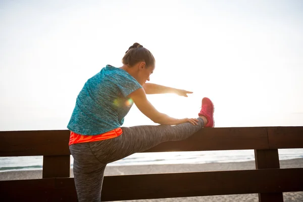 Closeup on fitness young woman stretching on beach in the evenin — Stock Photo, Image