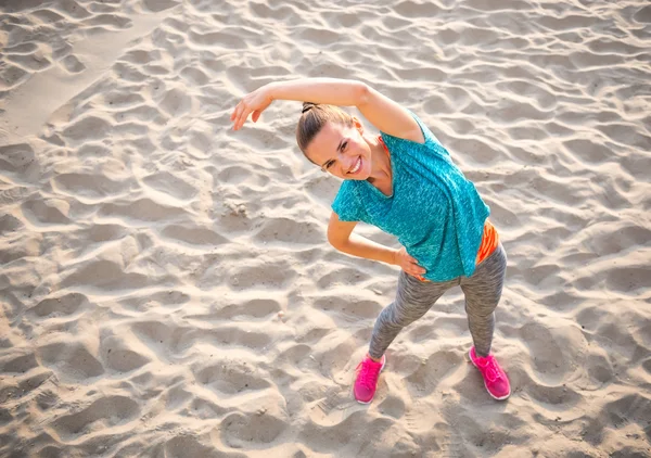 Fitness jeune femme étirant sur la plage — Photo