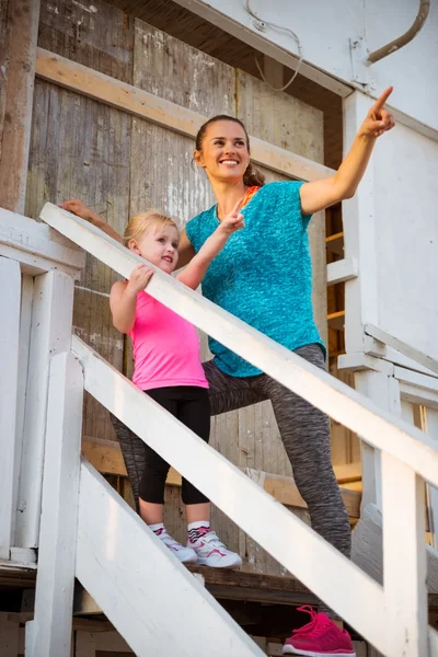 Gezonde moeder en babymeisje permanent op de trappen van strandhuis een — Stockfoto